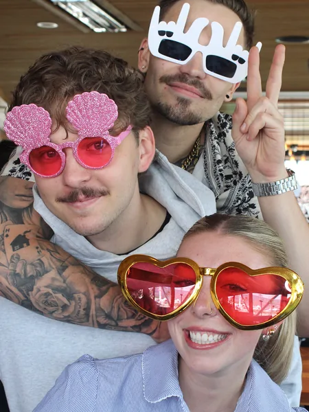 Three friends hugging and having fun with props at an Okanagan photo booth.